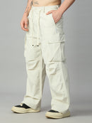 A person wearing off-white cargo pants with a drawstring waist, side cargo pockets, and wide legs, paired with black and cream platform sneakers against a plain gray studio background.
