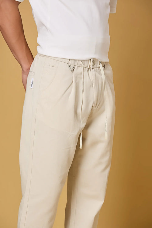 Close-up of beige trousers waist string, triangle ring, and fabric texture.
