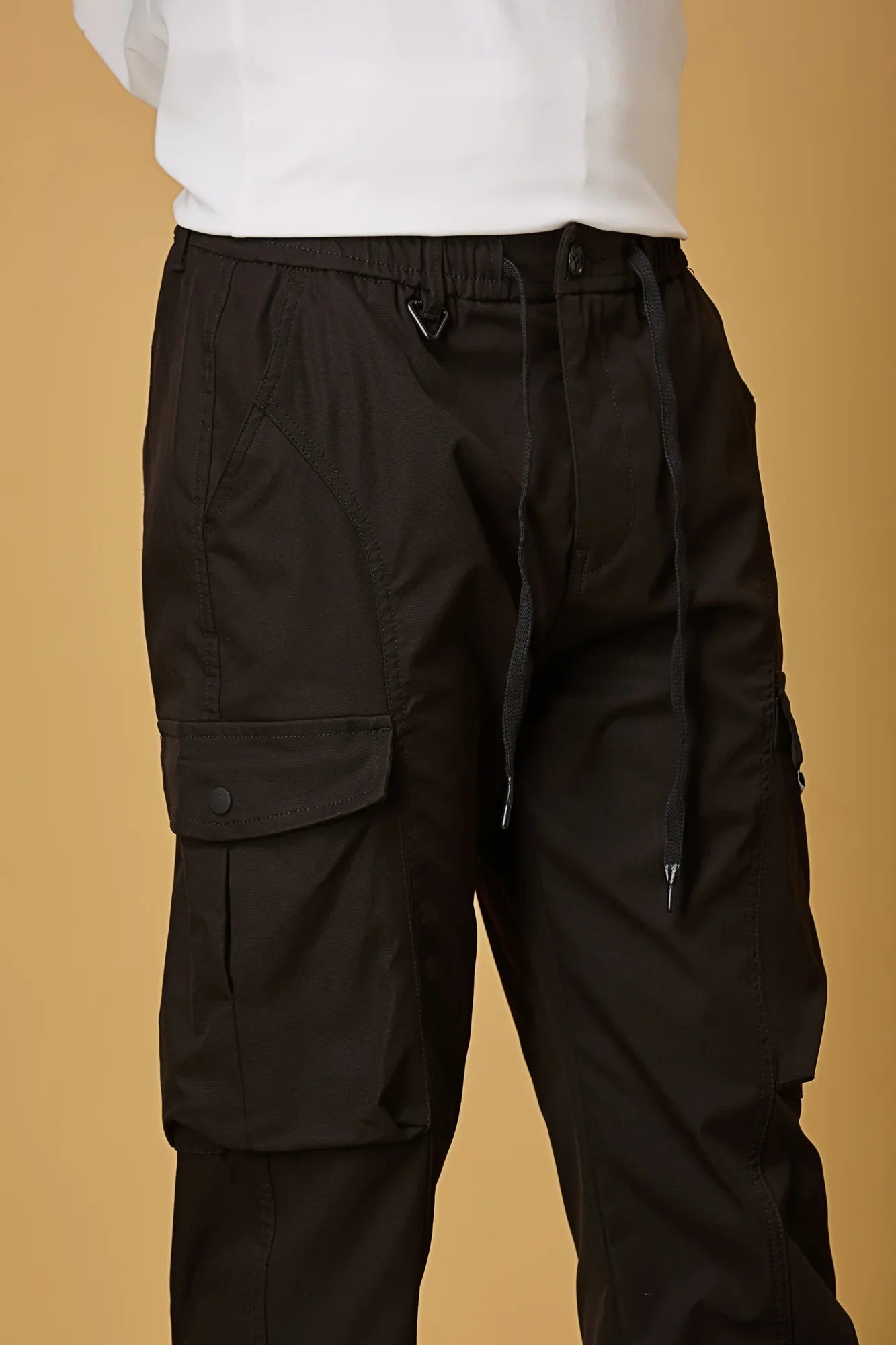 Close-up of black cargo pants, waist string and pocket detailing.