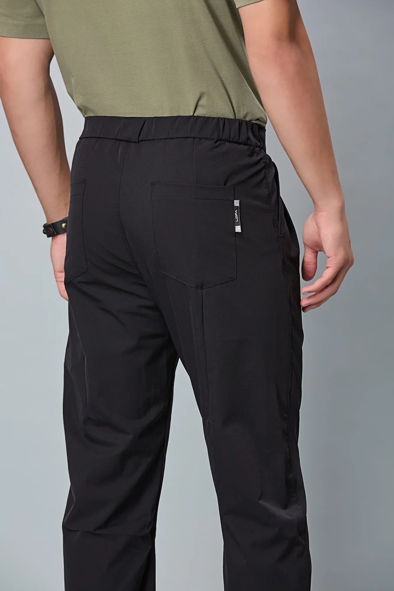Close-up of black trousers belt, elastic waist, and pleated design details