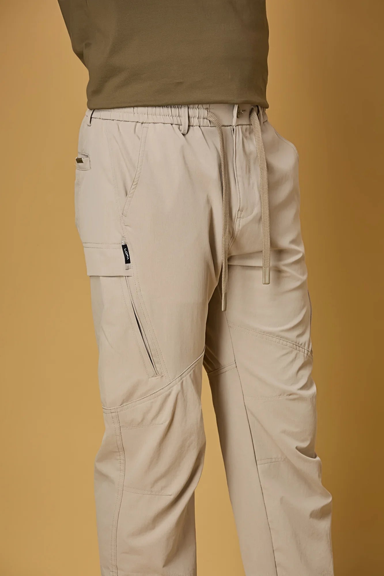 Close-up of khaki trousers waist strings, side pockets, and smooth fabric texture.