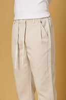 Close-up of waist string, press button, and fabric texture on beige trousers.