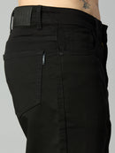 Close-up of waistband, button closure, and premium stitching on men's black baggy stretch denim jeans