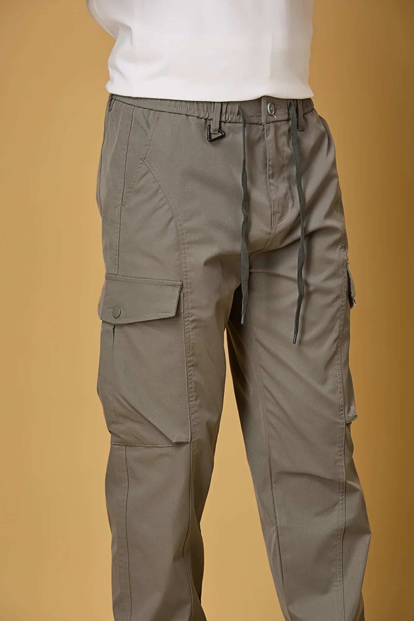 Close-up of grey cargo pants, waist string and pocket detailing.