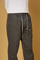 Close-up of grey trousers waist string, triangle ring, and fabric texture.